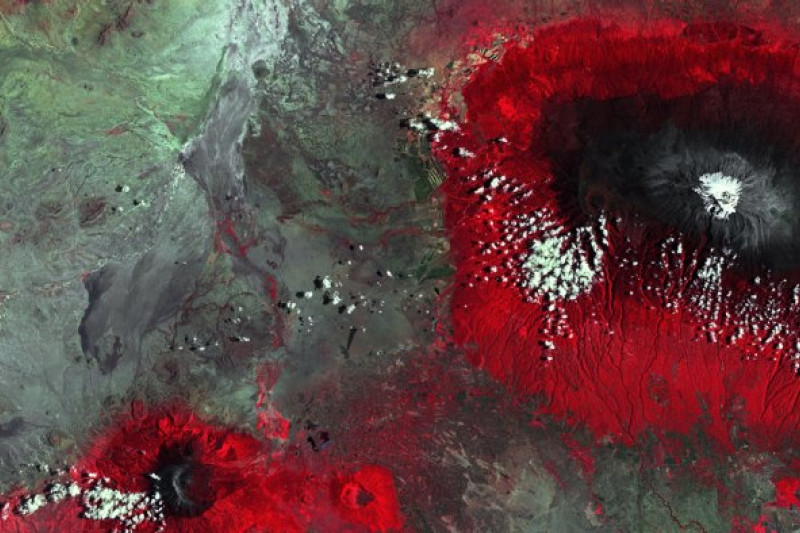 Von oben fotografierter Berg – der Kilimandscharo – mit weißer Spitze und rotem Gelände