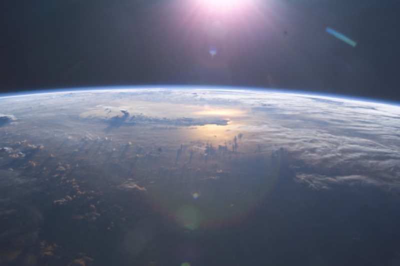 Aus dem Weltraum von oben fotografierter Ausschnitt von der Oberfläche der Erde mit von oben kommenden Sonnenstrahlen.